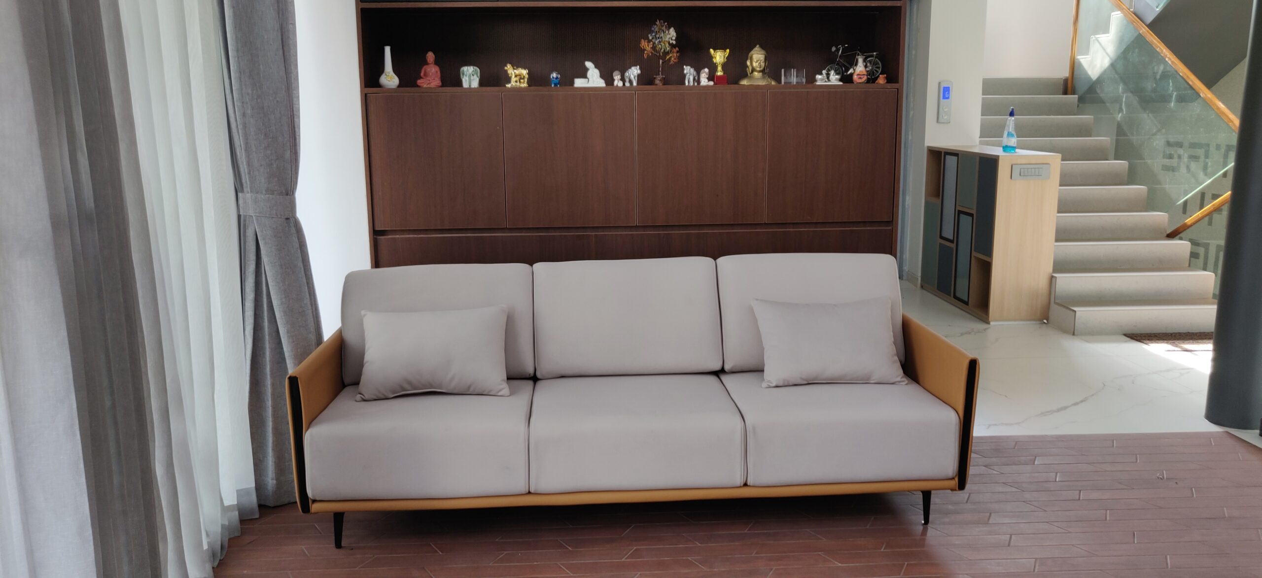 Cream fabric sofa with a wooden frame in a living room with dark wood wall panelling