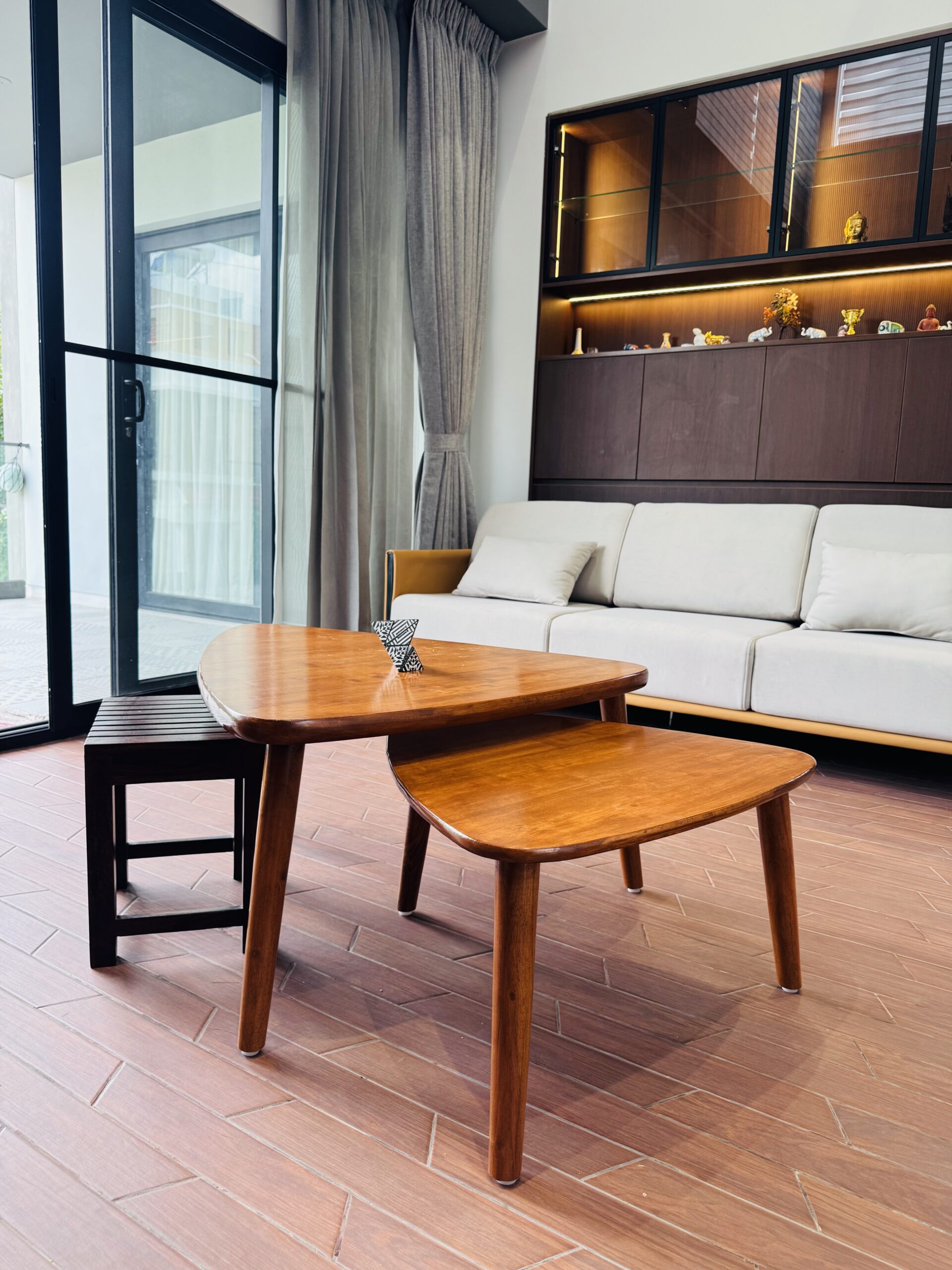 Wooden nesting coffee tables in front of a cream sofa in a living room