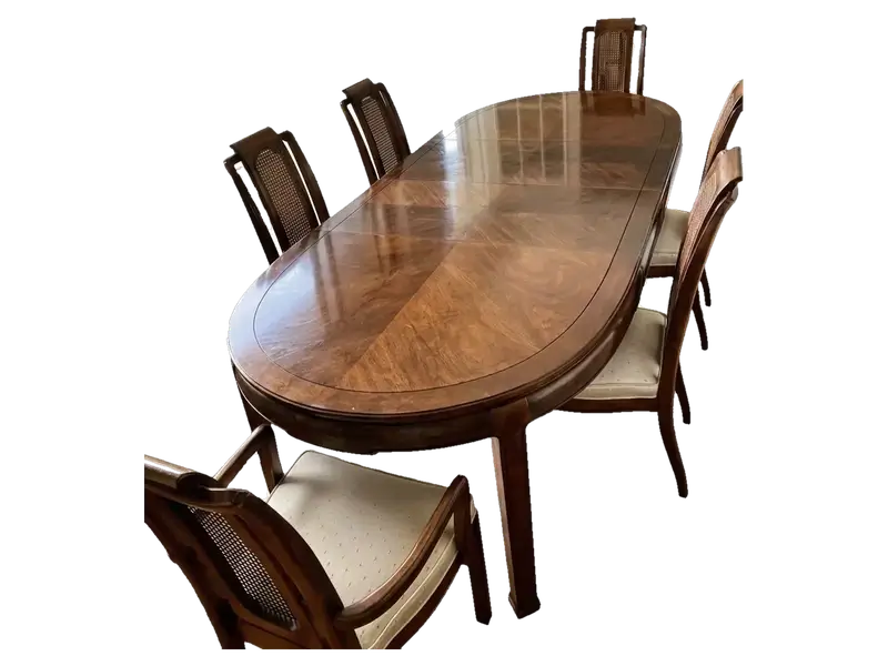 Oval 6 seater wooden dining table with a polished top and cane-back chairs