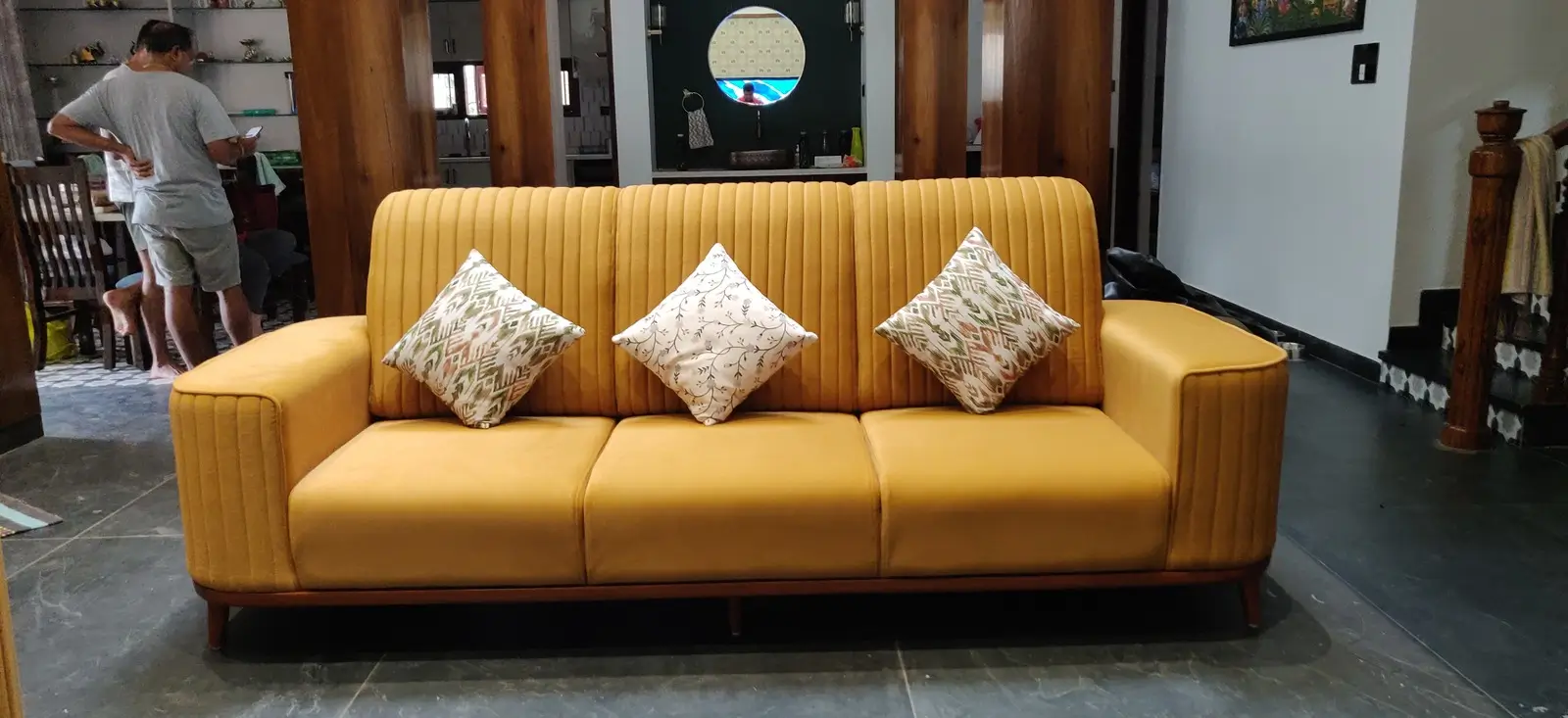 Mustard 3 seater sofa with channel-tufted back and wooden base, styled with floral cushions